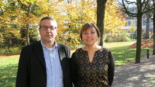 Ein Mann und eine Frau vor Herbstbäumen.