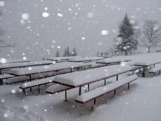 Bänke und Stühle sind von 30 Zentimeter Neuschnee bedeckt, es schneit stark.