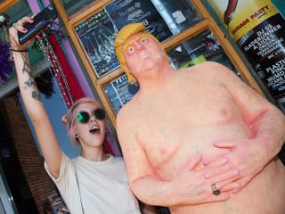 Statue eines nackten Mannes, zwei Männer machen Selfies mit ihr. 