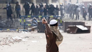 Ein Mann wirft Steine auf Polizisten. Die Szene spielt sich in Kairo ab.