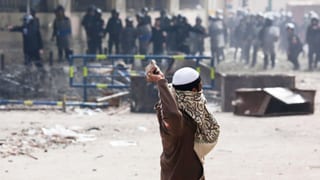Ein Mann wirft Steine auf Polizisten. Die Szene spielt sich in Kairo ab. Ein Mann wirft Steine auf Polizisten. Die Szene spielt sich in Kairo ab.