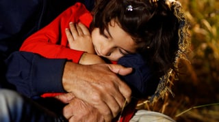 Ein syrischer Flüchtling in Serbien hält seine schlafende Tocher in den Armen. 