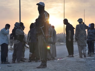 Bewaffnete und vermummte Männer stehen auf der Strasse im Irak.