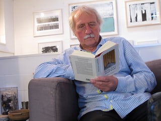 Ernst Wohlwend sitzt lesend in einem Sessel.