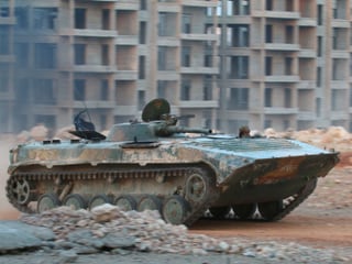 Ein Panzer fährt vor leeren Wohnblöcken