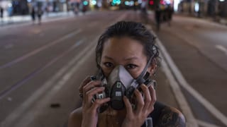Junge Frau mit Gasmaske auf nächtlicher Hongkonger Strasse. Junge Frau mit Gasmaske auf nächtlicher Hongkonger Strasse.