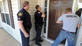 Polizisten lassen eine Tür für eine Zwangsräumung aufsperren.