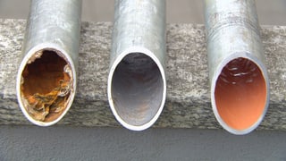 Drei Rohre in verschiedenen Stadien: korrodiert, gesäubert und mit Epoxidharz ausgekleidet.