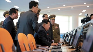 Nordkoreas Machthaber Kim Jong-un sitzt an einem Computer, hinter ihm stehen Beamte und Militärs im sogenannten Sci-Tech Complex in Pjöngjang.
