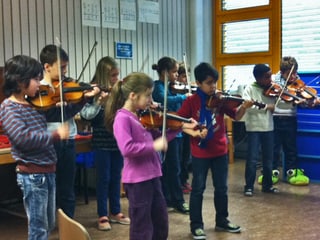 Eine Gruppe von Schulkindern spielt Geige.
