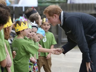 Schulkinder mit gebastelten Kronen empfangen Prinz Harry an ihrer Schule. Schulkinder mit gebastelten Kronen empfangen Prinz Harry an ihrer Schule.