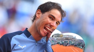 Rafael Nadal beisst in einen Pokal.