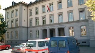 Gebäude aus Stein, davor Polizeiautos. Gebäude aus Stein, davor Polizeiautos.