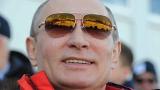 Wladimir Putin mit Sonnenbrille, in der sich die Berge von Sotschi spiegeln.