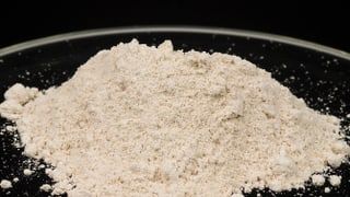 Ein Häufchen weisses Pulver auf einem dunklen Teller. Ein Häufchen weisses Pulver auf einem dunklen Teller.