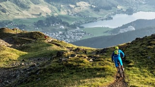 Ein Biker fährt einen schmalen Weg hinunter ins Tal. Ein Biker fährt einen schmalen Weg hinunter ins Tal.