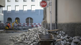 Baustelle mit Schubkarre, Pflastersteinen und Bagger Baustelle mit Schubkarre, Pflastersteinen und Bagger