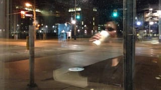Eine leere Strassenkreuzung, in einer Scheibe die Reflexion einer jungen Frau, die Kaffee trinkt. Eine leere Strassenkreuzung, in einer Scheibe die Reflexion einer jungen Frau, die Kaffee trinkt.