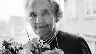 Eine ältere Dame vor einem Blumenstrauss