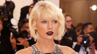 Taylor Swift mit kurzen blonden Haaren und dunklem Lippenstift.