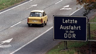 Strasse mit Trabi und Schild: «Letzte Ausfahrt in der DDR»
