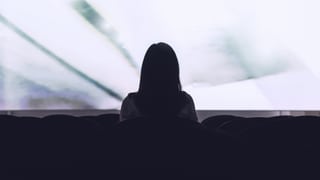 Eine Frau sitzt allein im Kino. Sicht von Hinten, vorne die Leinwand. Eine Frau sitzt allein im Kino. Sicht von Hinten, vorne die Leinwand.