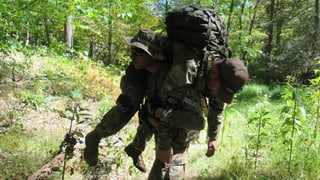 Ein Miliz-Soldat transportiert einen Kameraden auf der Schulter.