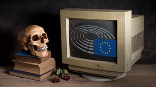 Ein Totenschädel steht neben einem Computerbildschirm, auf dem das Logo des Europäischen Parlaments zu sehen ist.