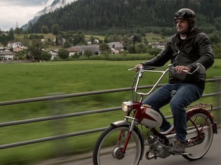 Ein Mann fährt auf einem Töffli.