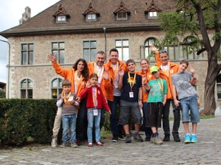 Das Gruppenfoto zeigt die beiden Familien und Sven Epiney in orangen Jacke im Freien vor dem Landesmuseum.
