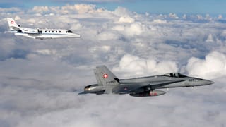 Ein F/A-18-Kampfjet begleitet den Bundesratsjet hoch über den Wolken.