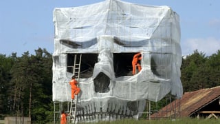 Greenpeace-Deponiebesetzer enthüllen ein monumentales Mahnmal in Form eines Totenkopfes. 