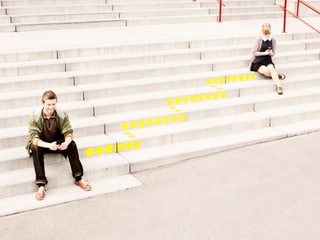 Ein Mann sitzt auf einer Treppe. Er schaut lächelnd in ein Smartphone. Eine gepunktete Linie führt von ihm weg die Treppe hinauf. Ein Mann sitzt auf einer Treppe. Er schaut lächelnd in ein Smartphone. Eine gepunktete Linie führt von ihm weg die Treppe hinauf.