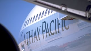 Schriftzug Cathay Pacific an einem Flugzeug von unten fotografiert mit einem Teil des Flügels im Vordergrund
