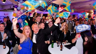 Jubelnde Parteimitglieder schwenken Schweden-Flaggen.
