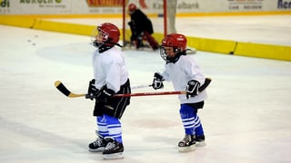 Zwei Kinder in Eishockey-Montur auf dem Eisfeld