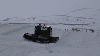 Ein Pistenraupen-Fahrzeug fährt durch den Schnee.