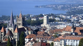 Blick auf die Gebäude der Stadt Lausanne mit der Kathedrale und dem See im Hintergrund.