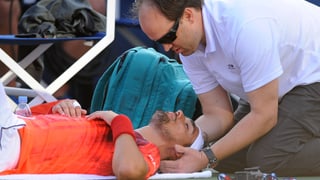 Fabio Fognini liegt am Boden und muss sich vom Physiotherapeuten am Rücken behandeln lassen.