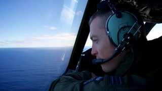Pilot eines neuseeländischen Suchflugzeugs schaut aus dem Fenster aufs Meer.