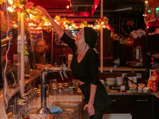 Eine Frau mit schwarzer Mütze und schwarzem Shirt in einer dunklen Bar Eine Frau mit schwarzer Mütze und schwarzem Shirt in einer dunklen Bar