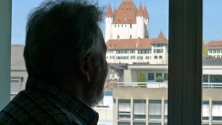 Walter steht im Gegenlicht vor einem Fenster im Regionalzentrum Oberland der Stiftung Berner Gesundheit, gegenüber befindet sich das Thuner Schloss.