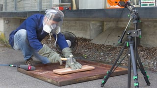 Mann mit Gesichtsschutz und Handschuhen treibt einen Nagel durch den Akku. Mann mit Gesichtsschutz und Handschuhen treibt einen Nagel durch den Akku.