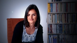 Bettina Oberli sitzt vor einem Bücherregal.