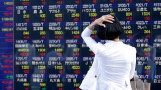Frau schaut Börsenkurse an und hält sich den Kopf dabei