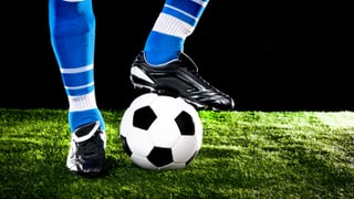 Beine eines Fussballers mit einem Ball