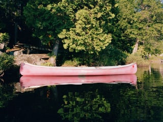 Ein leeres Kanu am bewaldeten Ufer eines Sees.