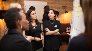 Vier Frauen stehen um ein Flip Chart und diskutieren. Vier Frauen stehen um ein Flip Chart und diskutieren.