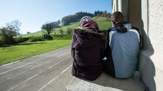 Zwei Asylsuchende von hinten, sie sitzen auf einem Absatz vor der Asylunterkunft in Schafhausen.