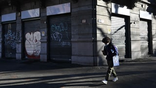 Eine Person läuft in Mailand an einem geschlossenen Geschäft vorüber.